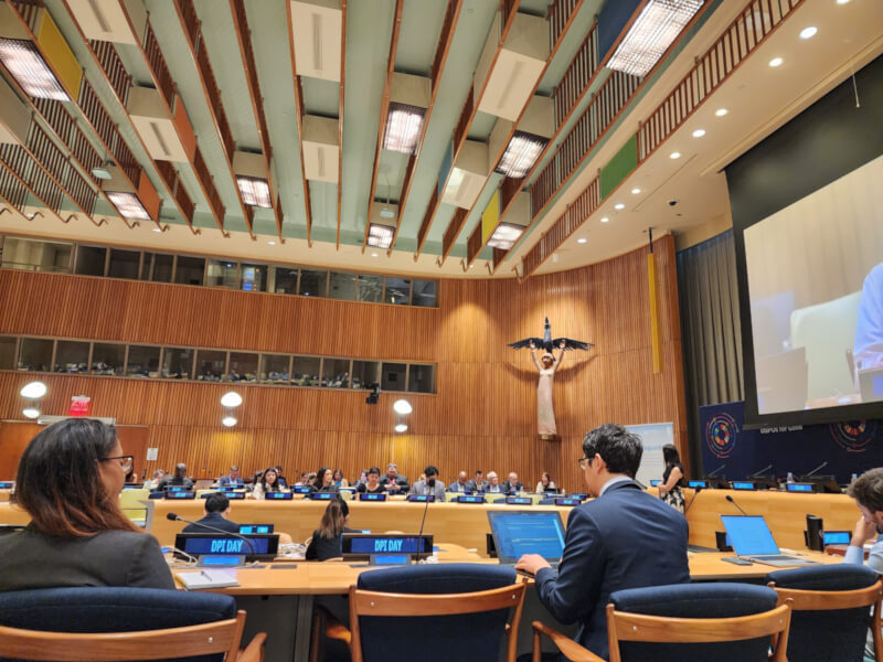 Thumbnail that shows participants at UN Open Source Week seated at tables with laptops and microphones inside a conference room at United Nations Headquarters in New York City.